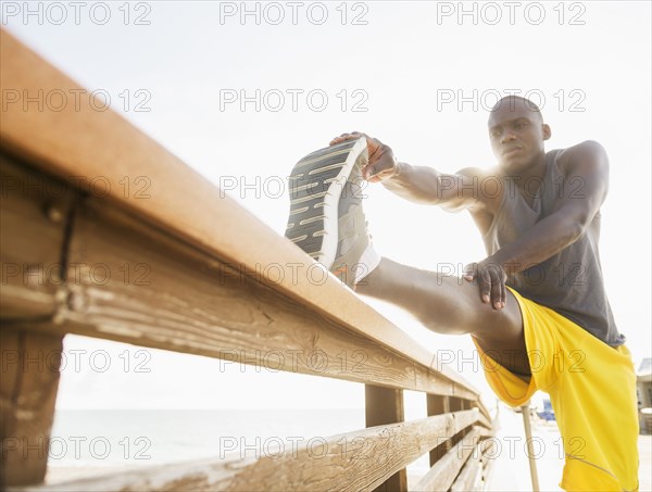 Mixed race runner stretching leg on banister