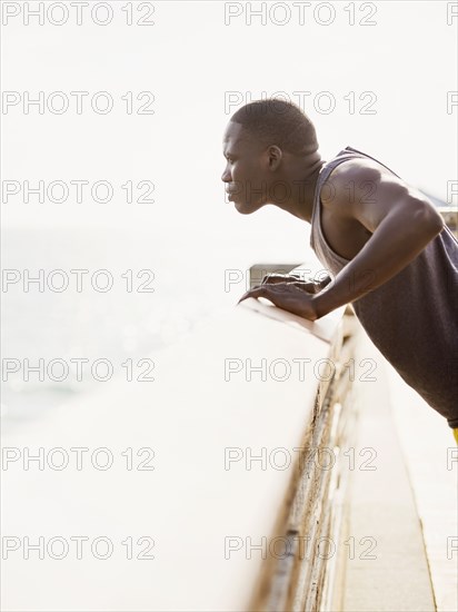 Mixed race runner stretching on banister