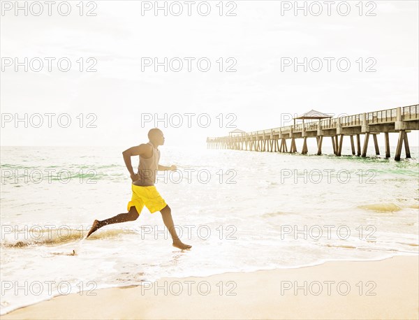 Mixed race barefoot man running on beach