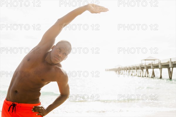 Mixed race man stretching on beach