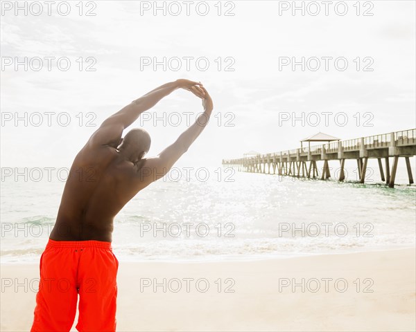 Mixed race man stretching on beach