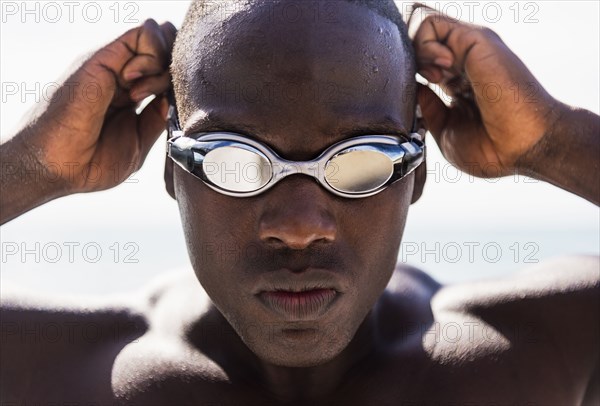 Mixed race swimmer putting on goggles