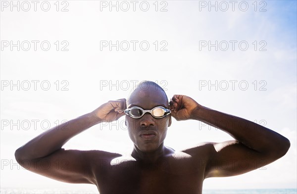 Mixed race swimmer putting on goggles