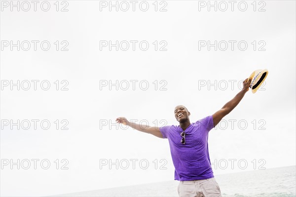 Mixed race man with arms outstretched on beach