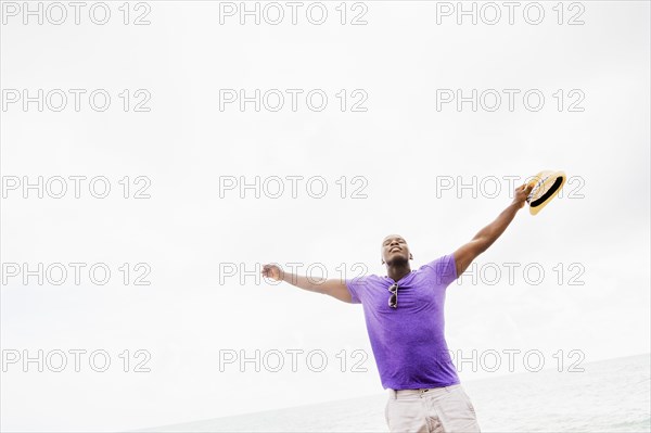 Mixed race man with arms outstretched on beach