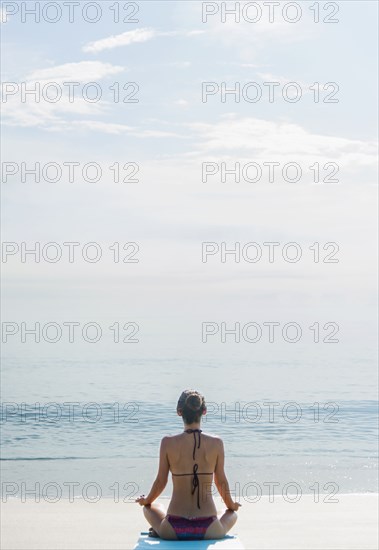 Caucasian woman meditating on beach