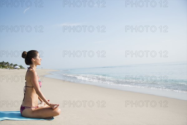 Caucasian woman meditating on beach