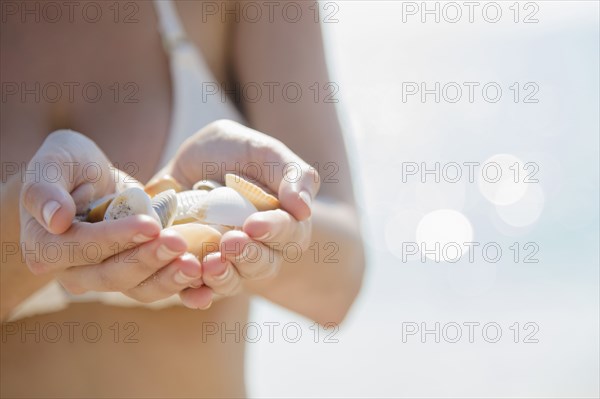 Close up of Caucasian woman holding seashells at beach