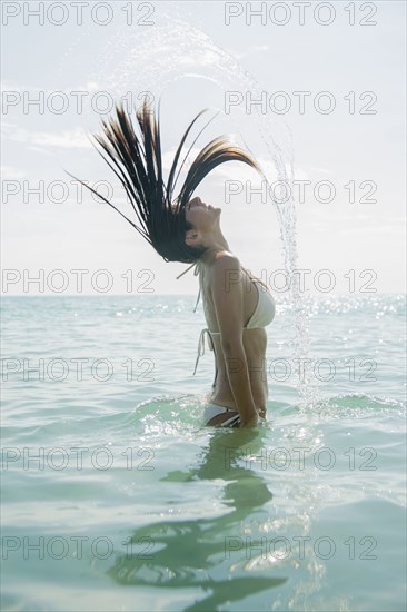 Caucasian woman splashing hair in ocean