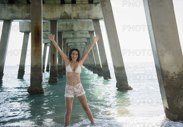 Caucasian woman standing under pier at ocean