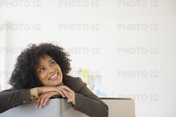 Businesswoman leaning over cubicle wall in office