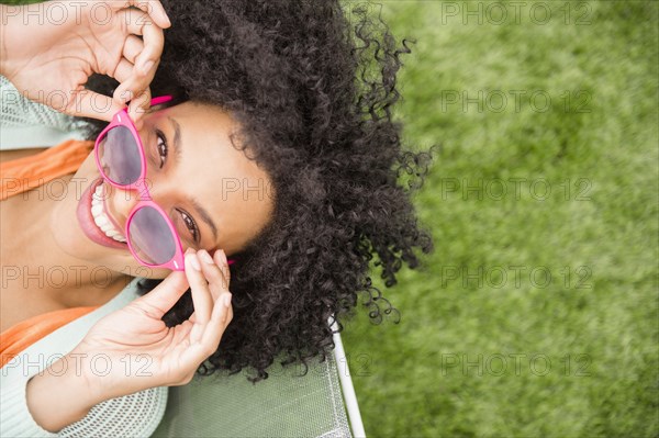 High angle view of woman holding sunglasses in chair outdoors