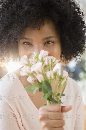 Woman smelling bouquet of roses indoors