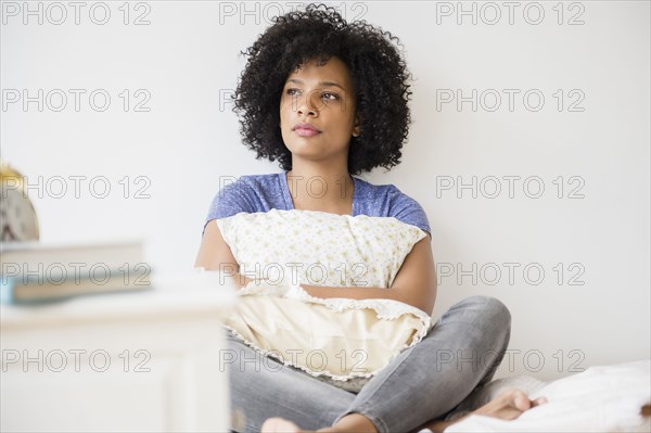 Lonely woman hugging pillow on bed