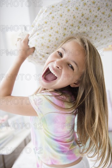 Caucasian girl having pillow fight in bedroom