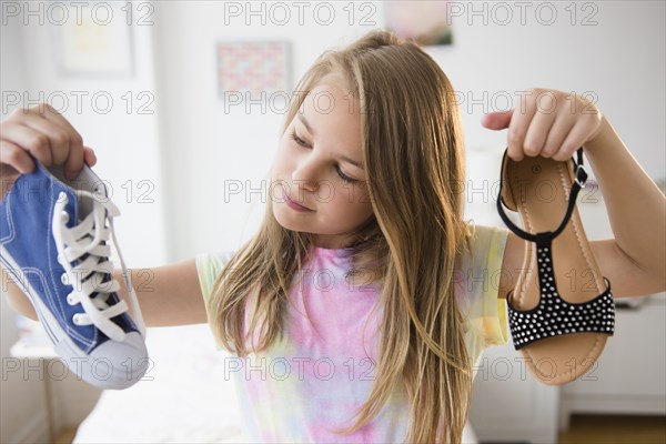 Caucasian girl picking shoes in bedroom