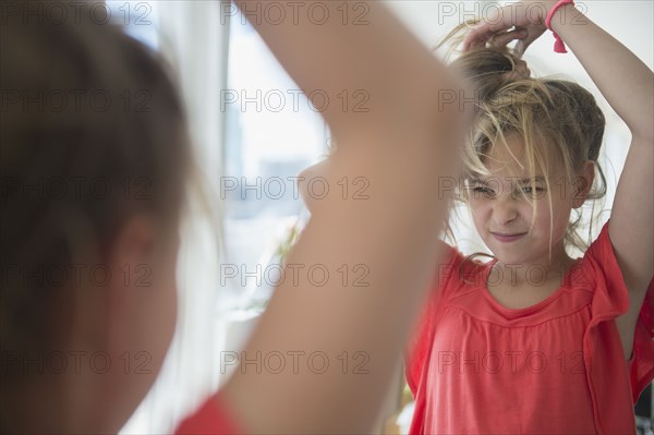 Caucasian girl playing with her hair at mirror