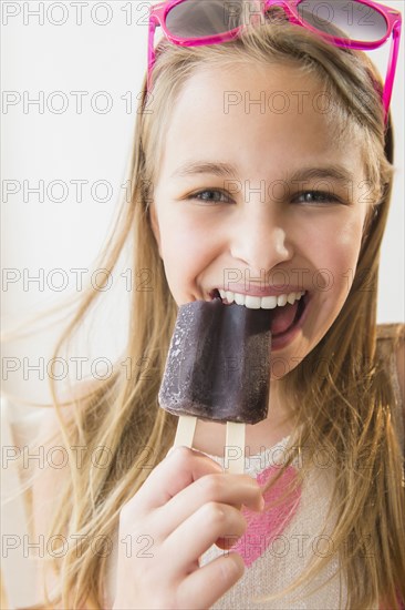 Caucasian girl eating grape popsicle