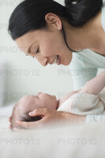 Asian mother holding baby on bed