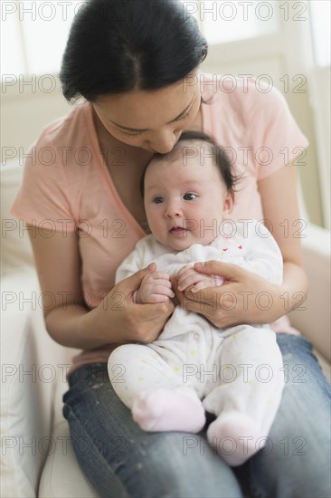 Asian mother holding baby in armchair