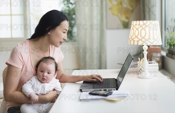 Asian mother with baby working from home