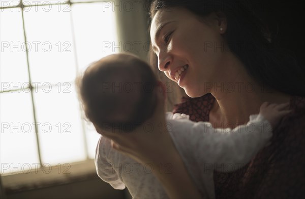 Asian mother holding baby near window