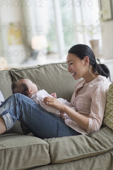 Asian mother playing with baby in living room