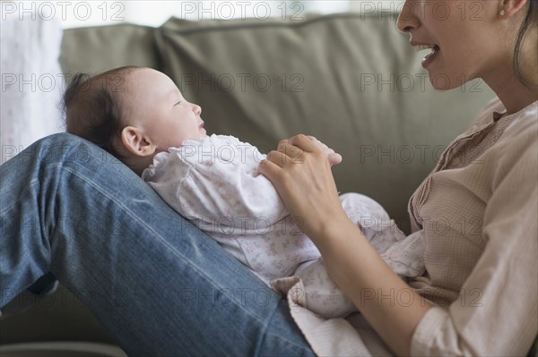 Asian mother playing with baby in living room