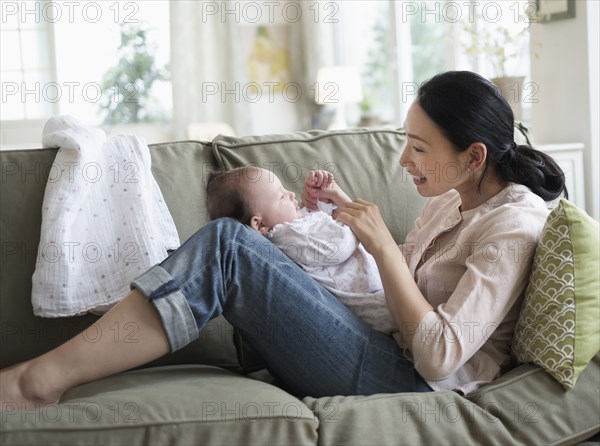 Asian mother playing with baby in living room