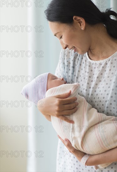 Asian mother holding newborn baby in hospital