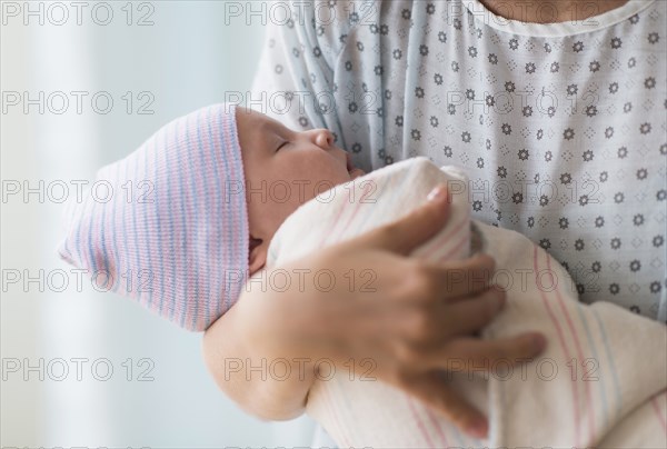 Asian mother holding newborn baby in hospital