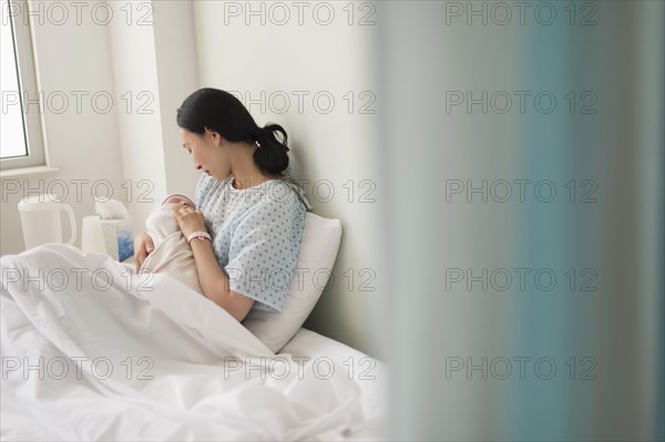 Asian mother holding newborn baby in hospital