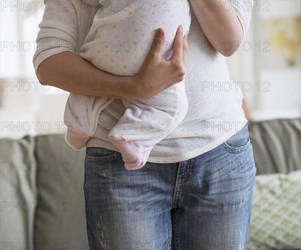 Asian mother holding baby in living room