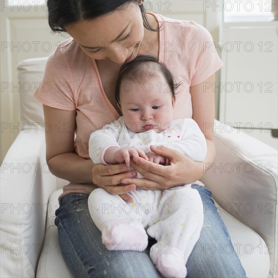 Asian mother playing with baby in living room