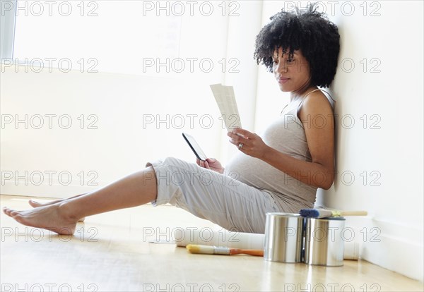 Pregnant African American mother examining paint swatches for nursery