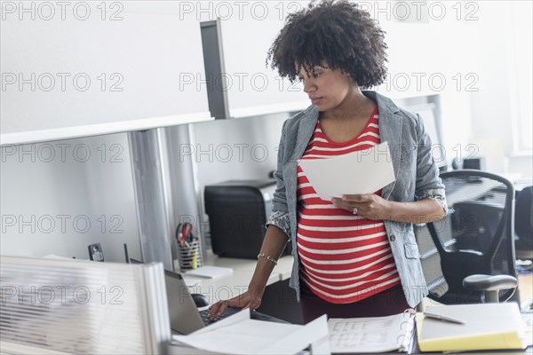 Pregnant African American businesswoman working in office