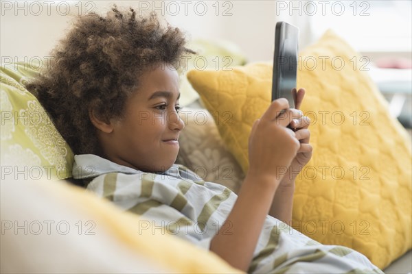 Mixed race boy using digital tablet in living room