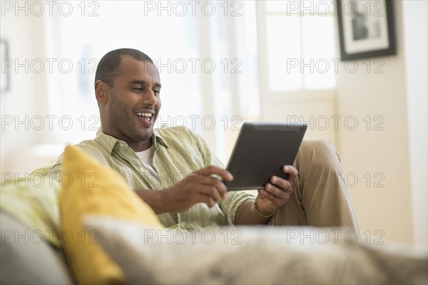 Mixed race man using digital tablet in living room