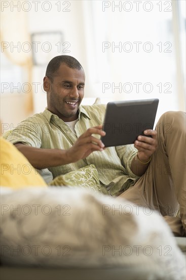 Mixed race man using digital tablet in living room