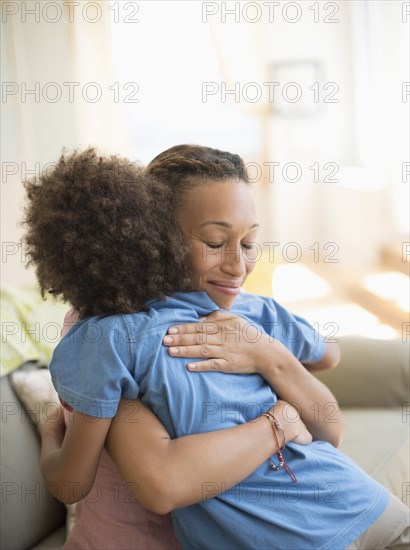 Mother and son hugging on sofa in living room