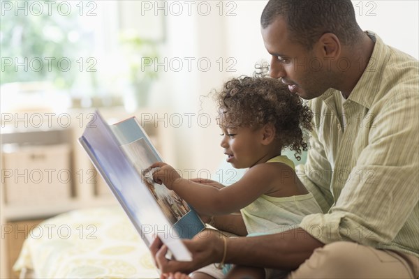 Father and daughter reading book on bed