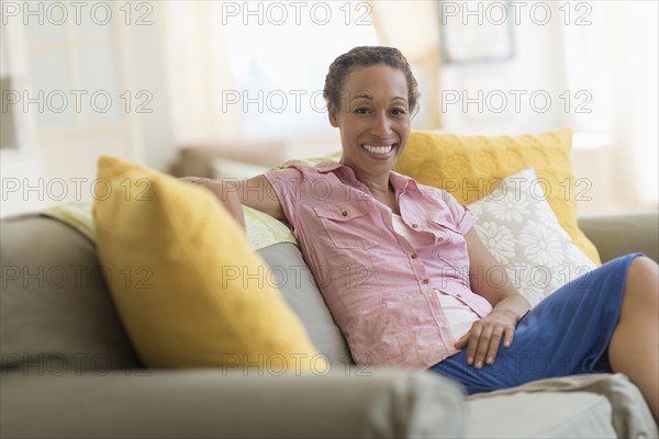 Mixed race woman smiling on sofa