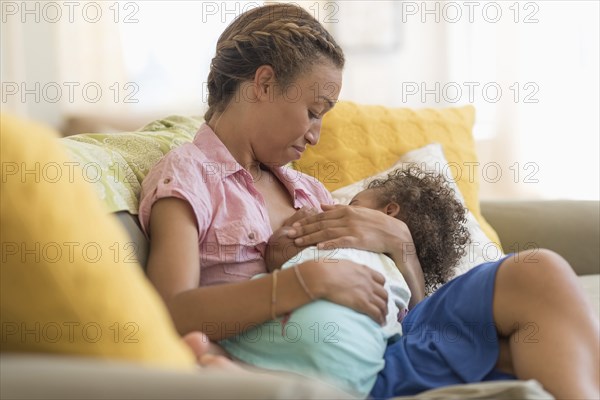 Mixed race mother nursing daughter in living room