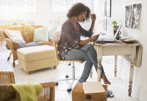 Mixed race woman using laptop in living room