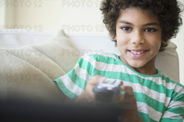 Mixed race boy watching television on sofa