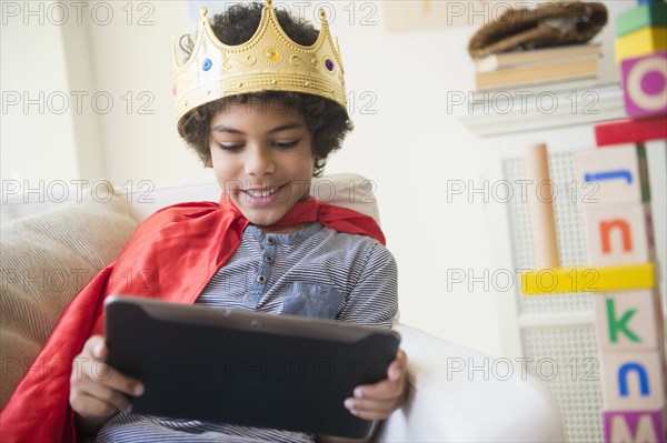 Mixed race boy in costume using digital tablet in living room