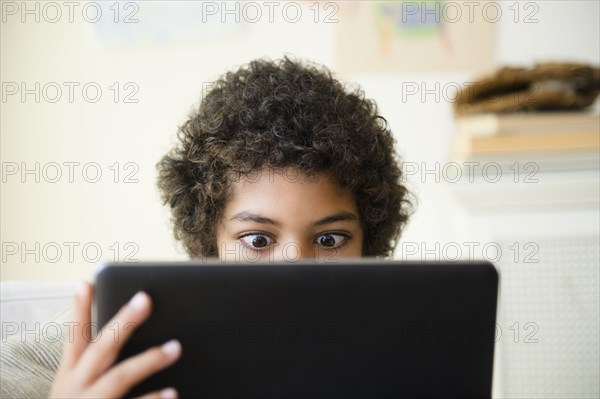 Mixed race boy using digital tablet in living room