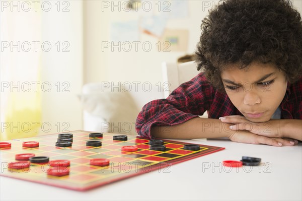 Angry mixed race boy losing game of checkers