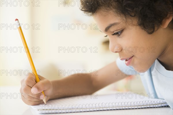 Mixed race boy writing in notebook