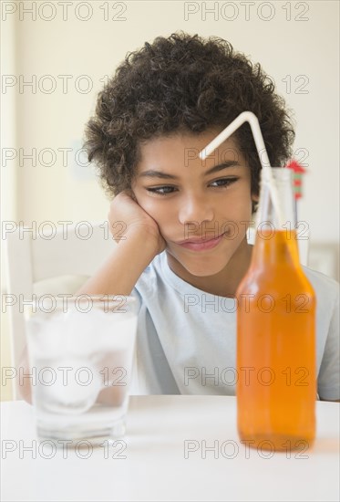 Mixed race boy choosing between soda and water